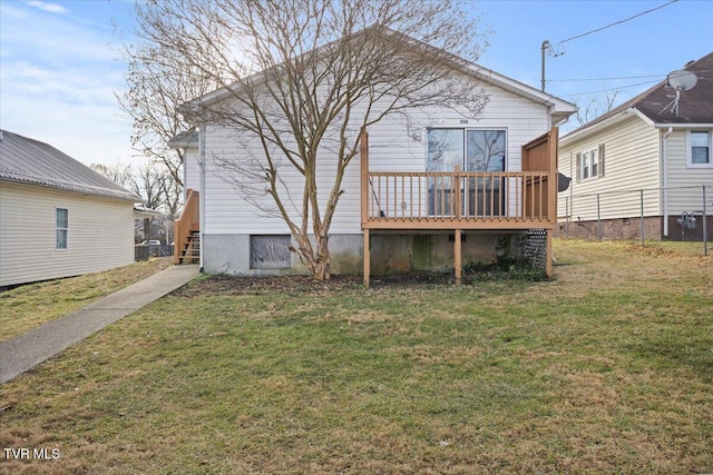 rear view of house featuring a lawn and a deck