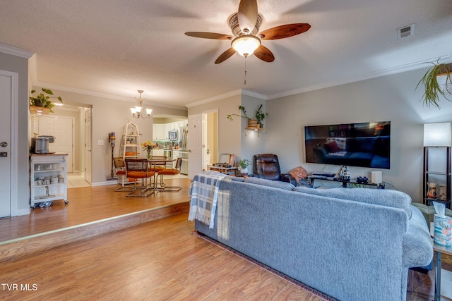 living room with crown molding, ceiling fan with notable chandelier, light hardwood / wood-style floors, and a textured ceiling