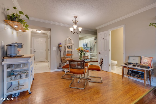 dining area featuring a textured ceiling, ornamental molding, light hardwood / wood-style floors, and a chandelier