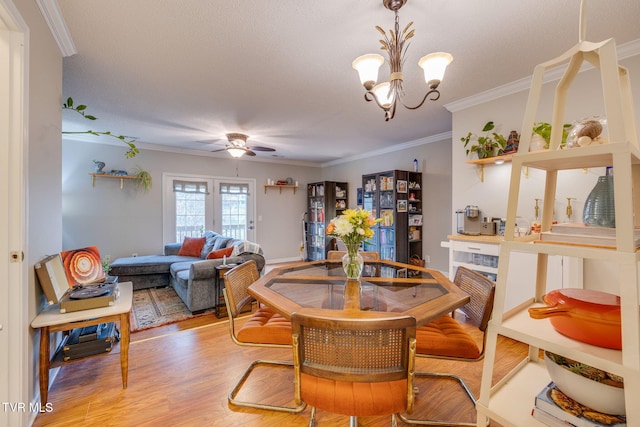 dining space featuring ornamental molding, ceiling fan with notable chandelier, and light wood-type flooring