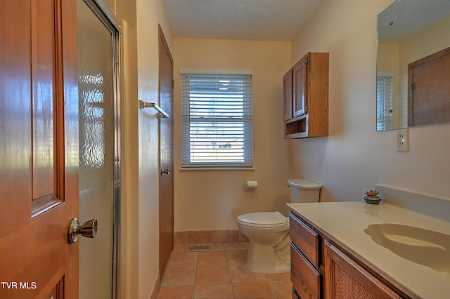 bathroom featuring tile patterned floors, toilet, a textured ceiling, vanity, and a shower with door