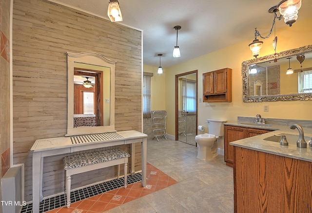 kitchen featuring hanging light fixtures, sink, light tile patterned floors, and wood walls