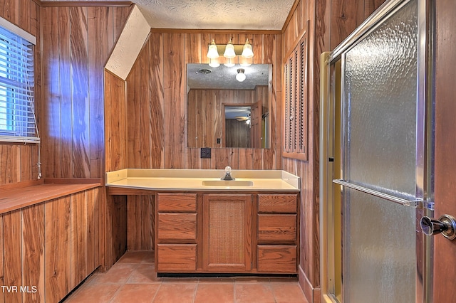 bathroom with tile patterned flooring, wooden walls, vanity, a textured ceiling, and walk in shower