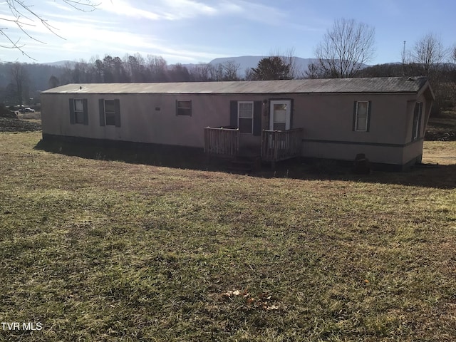 rear view of house featuring a mountain view and a lawn