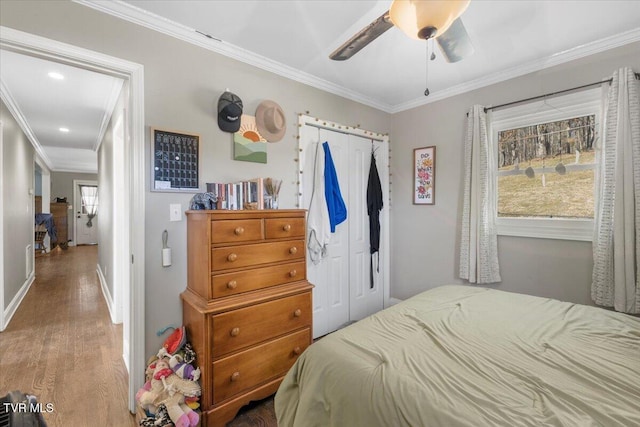 bedroom featuring hardwood / wood-style flooring, ornamental molding, a closet, and ceiling fan