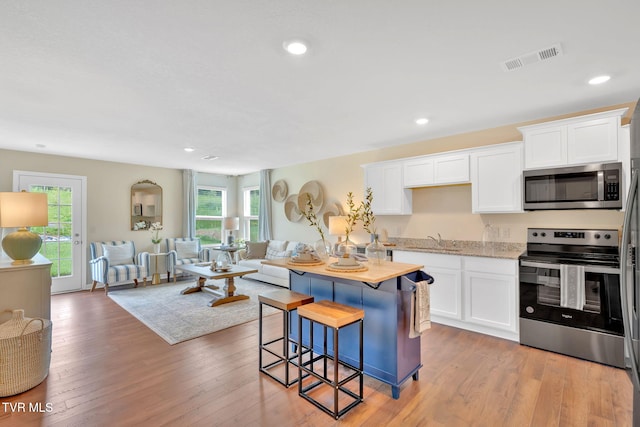 kitchen with appliances with stainless steel finishes, sink, white cabinets, and light hardwood / wood-style floors