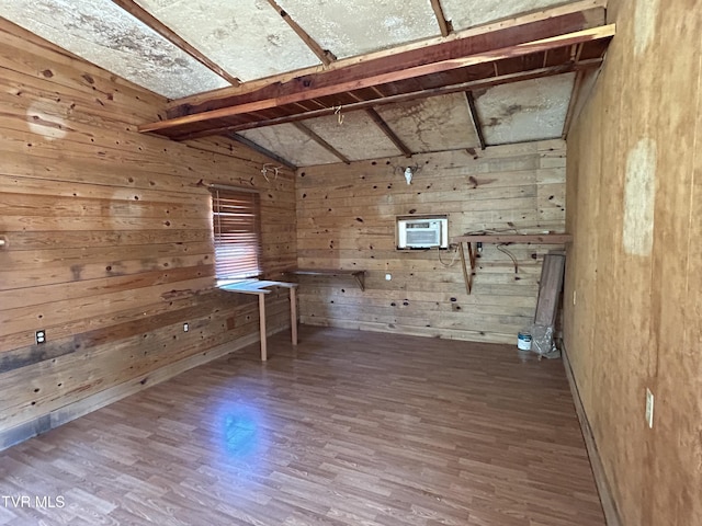 interior space with a wall mounted AC, lofted ceiling, hardwood / wood-style floors, and wooden walls