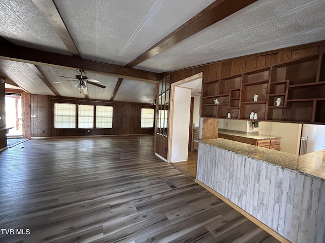 kitchen with wood walls, a textured ceiling, dark hardwood / wood-style floors, ceiling fan, and beam ceiling