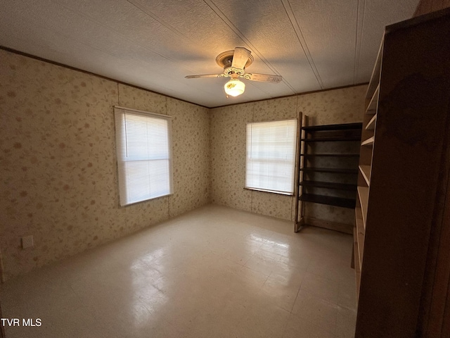 empty room featuring crown molding, ceiling fan, a textured ceiling, and a healthy amount of sunlight