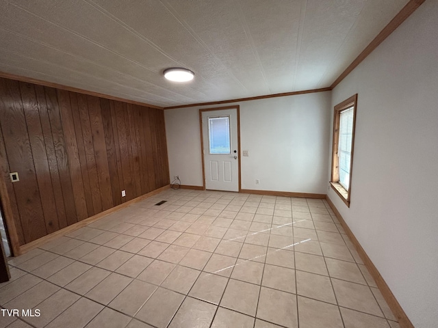 tiled spare room with ornamental molding and wood walls