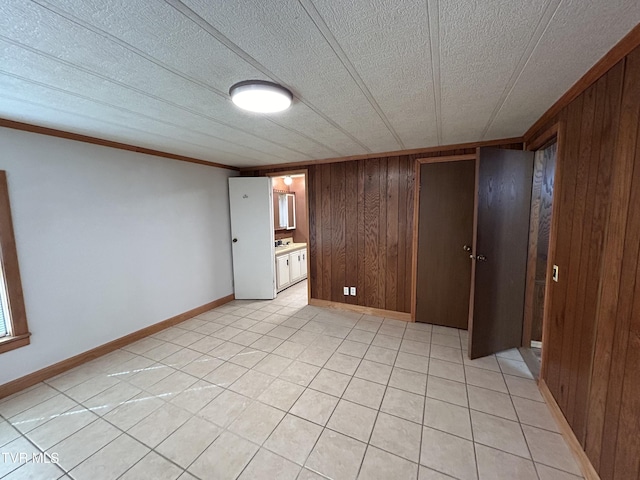 unfurnished bedroom featuring ornamental molding, a textured ceiling, and wood walls