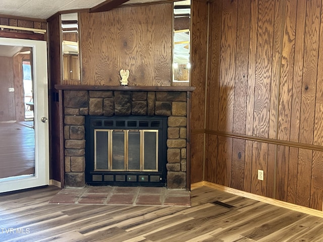 interior details featuring hardwood / wood-style floors, a stone fireplace, and wooden walls