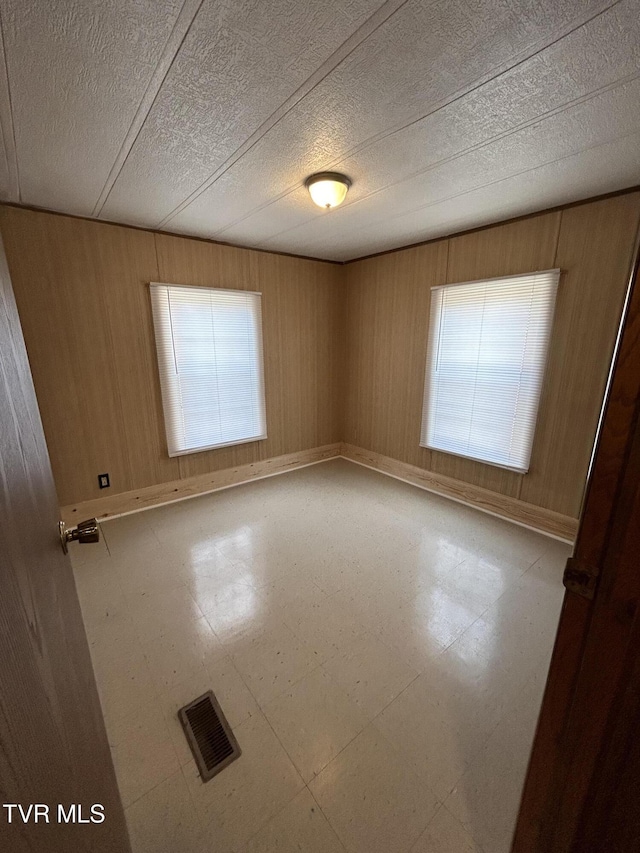 empty room with wooden walls and a textured ceiling