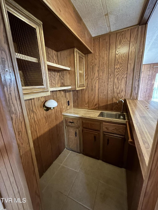 bathroom with tile patterned flooring, vanity, a textured ceiling, and wood walls