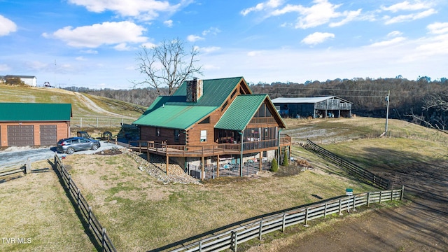 back of property featuring a rural view, a deck, and a lawn