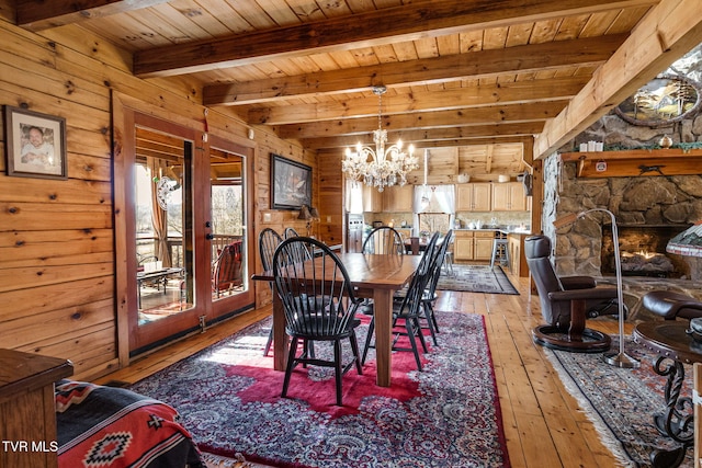 dining area with an inviting chandelier, wooden walls, light hardwood / wood-style floors, wooden ceiling, and beamed ceiling