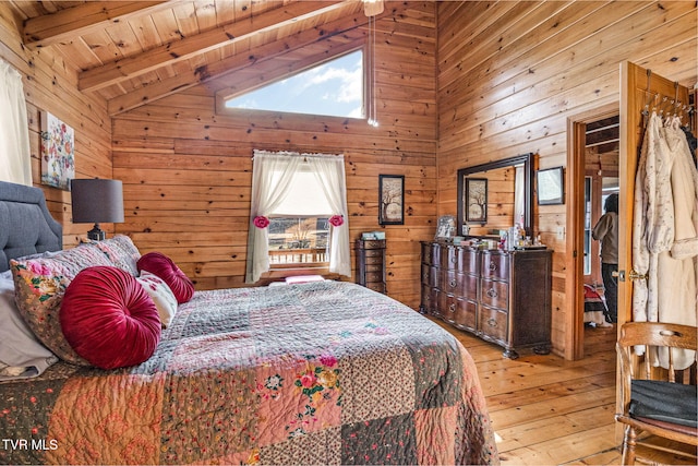 bedroom with lofted ceiling with beams, hardwood / wood-style floors, and wood walls