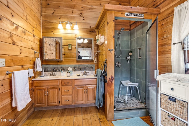 bathroom with walk in shower, vanity, hardwood / wood-style floors, and wood walls