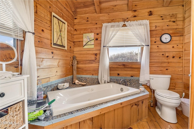 bathroom with toilet, wood walls, vanity, a bathing tub, and hardwood / wood-style flooring