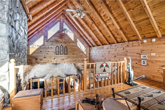 interior space featuring wood ceiling, hardwood / wood-style flooring, ceiling fan, lofted ceiling with beams, and wood walls