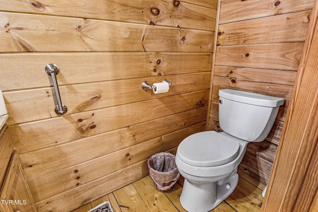 bathroom with wooden walls, wood-type flooring, and toilet