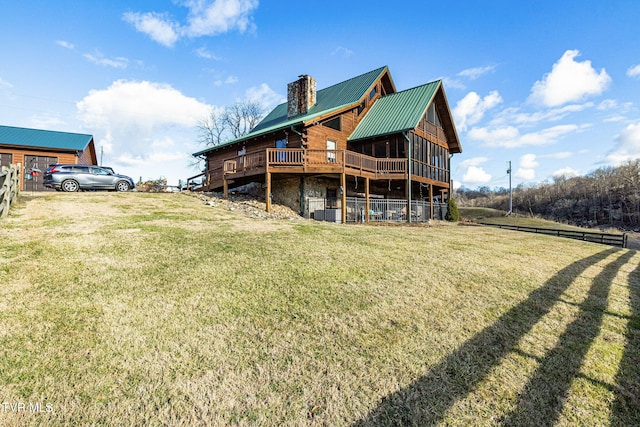 rear view of property featuring a wooden deck and a lawn