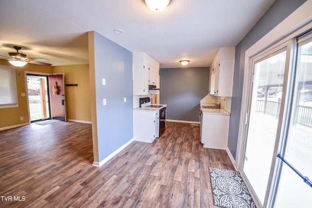 kitchen featuring wood-type flooring, black electric range, sink, and white cabinets