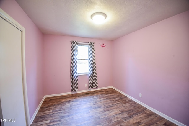 spare room with a textured ceiling and dark hardwood / wood-style flooring