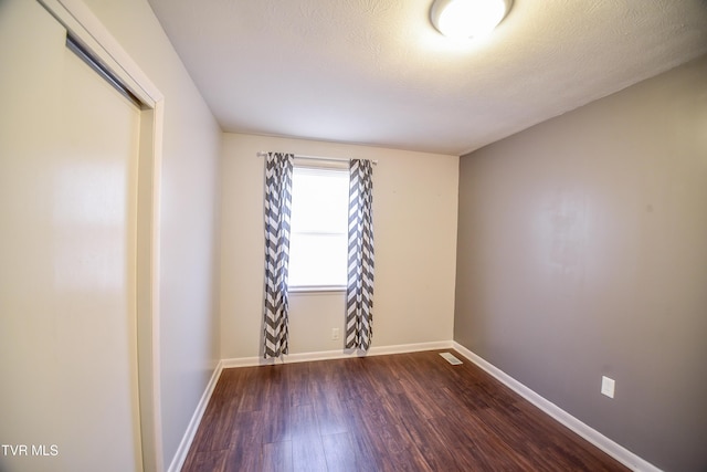 unfurnished room featuring dark hardwood / wood-style floors and a textured ceiling