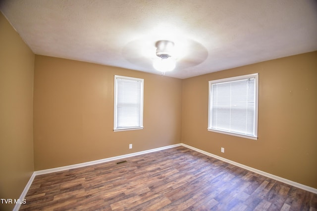 unfurnished room featuring ceiling fan, dark hardwood / wood-style flooring, and a textured ceiling