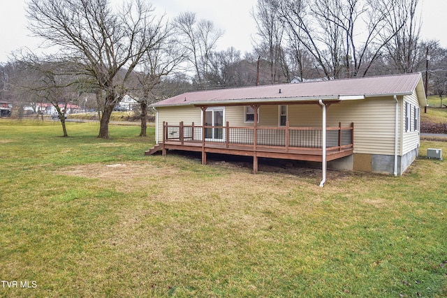 back of property with a wooden deck, a yard, and cooling unit