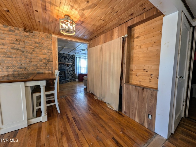 corridor with wood ceiling, dark wood-type flooring, and wooden walls