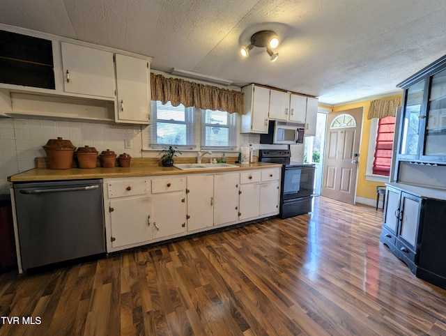 kitchen with dark wood-type flooring, sink, appliances with stainless steel finishes, white cabinets, and backsplash