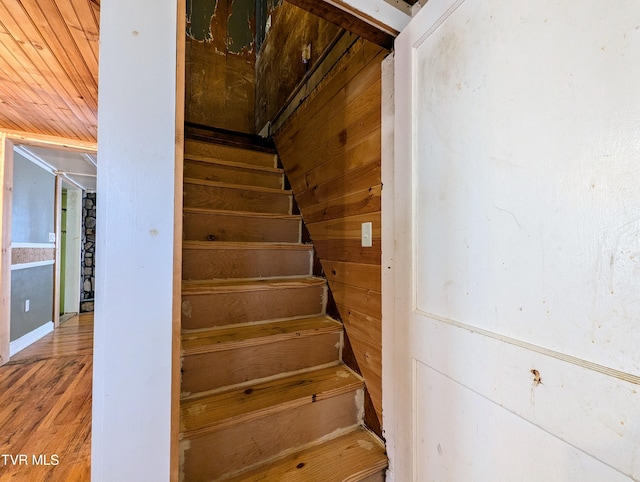 stairway with hardwood / wood-style floors and wood walls