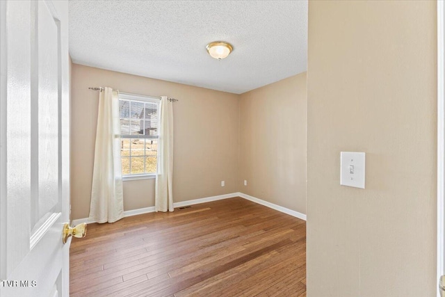 spare room featuring hardwood / wood-style floors and a textured ceiling