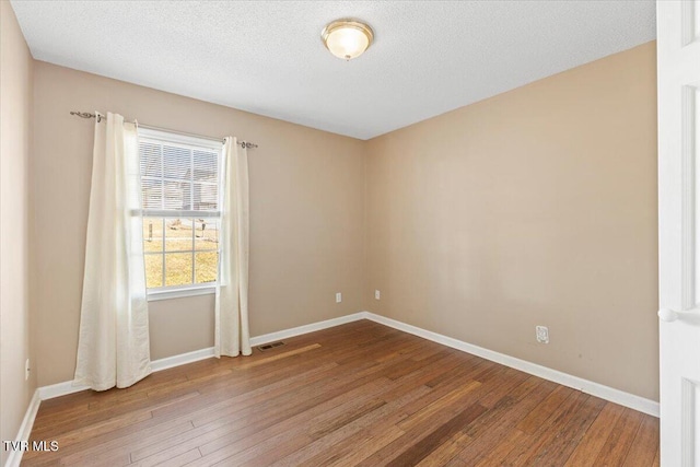 spare room with hardwood / wood-style floors and a textured ceiling