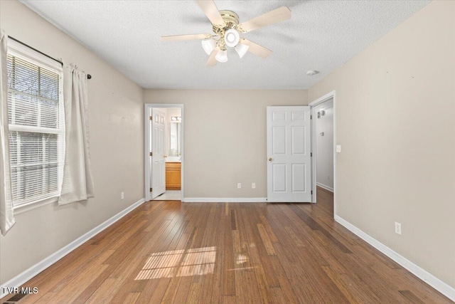 unfurnished bedroom with hardwood / wood-style flooring, ceiling fan, connected bathroom, and a textured ceiling