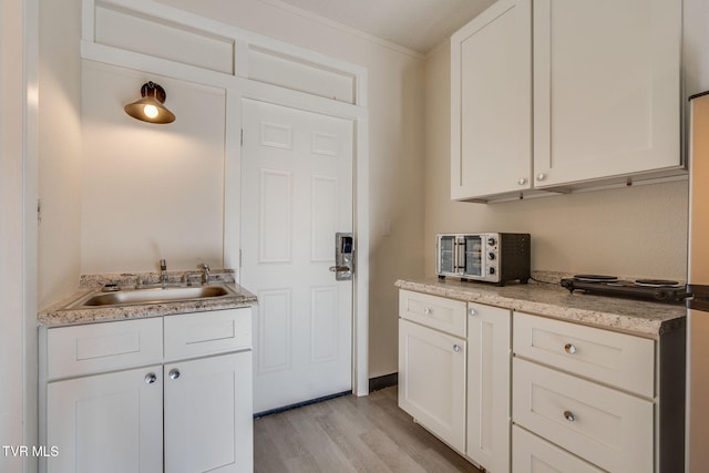 kitchen with white cabinetry, sink, and light hardwood / wood-style flooring