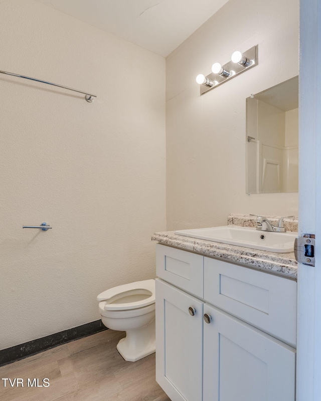 bathroom with walk in shower, vanity, toilet, and hardwood / wood-style floors