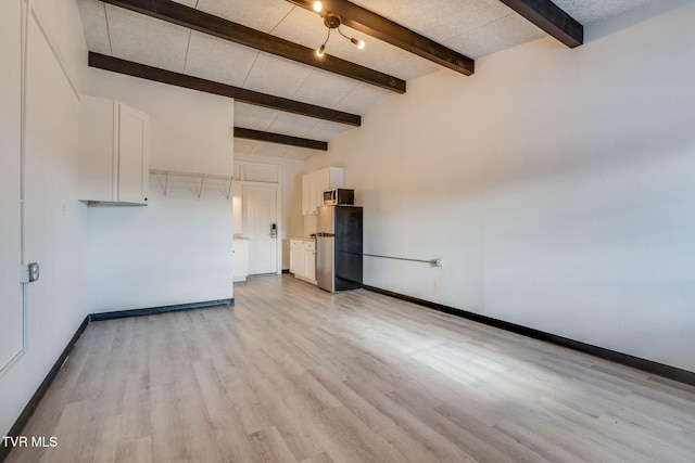 unfurnished living room with light hardwood / wood-style flooring, beamed ceiling, and a high ceiling