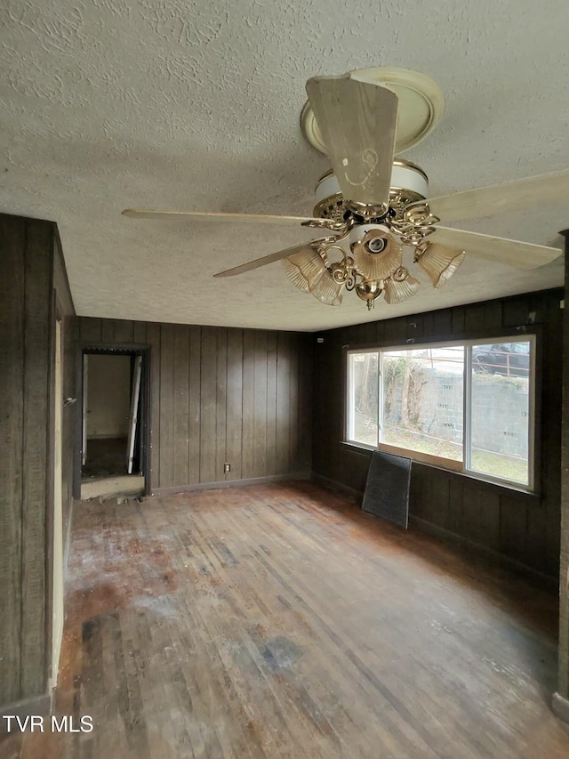 empty room with ceiling fan, a textured ceiling, and light wood-type flooring