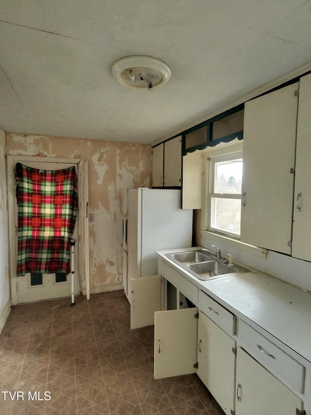 kitchen with white cabinetry, sink, and white refrigerator