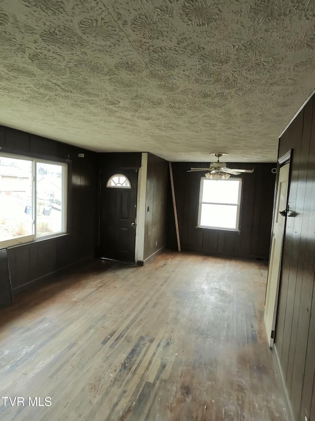 entrance foyer featuring ceiling fan, hardwood / wood-style flooring, a textured ceiling, and wood walls