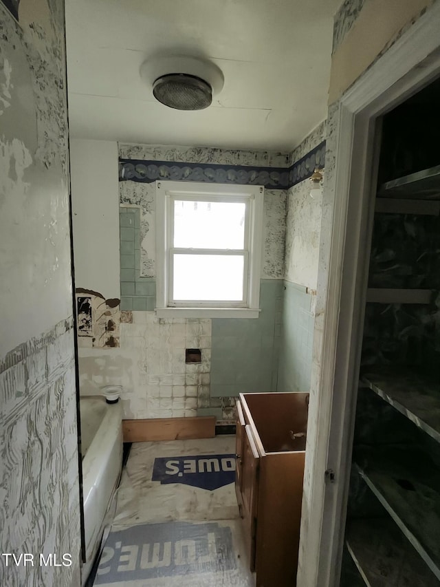 bathroom featuring vanity, tile walls, and a tub to relax in