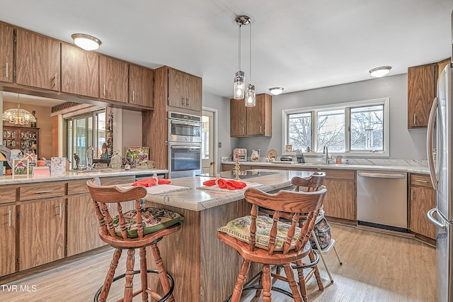 kitchen featuring appliances with stainless steel finishes, sink, light hardwood / wood-style floors, and decorative light fixtures