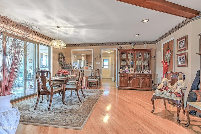 dining space featuring an inviting chandelier, light hardwood / wood-style flooring, and beamed ceiling