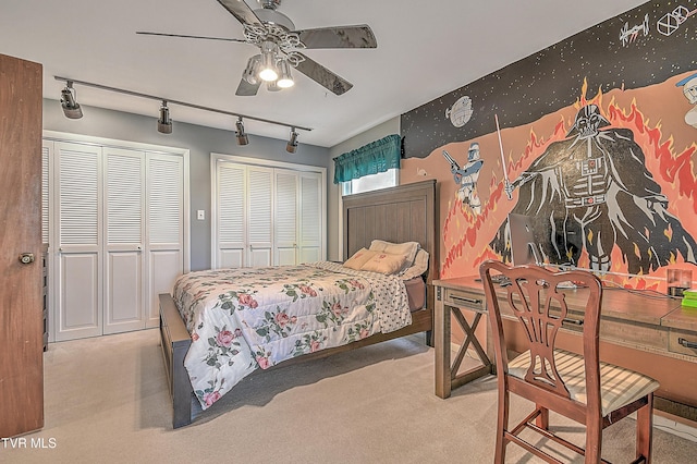 bedroom with multiple closets, light colored carpet, track lighting, and ceiling fan