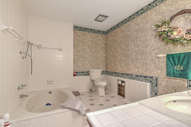 bathroom with tiled tub, sink, and toilet