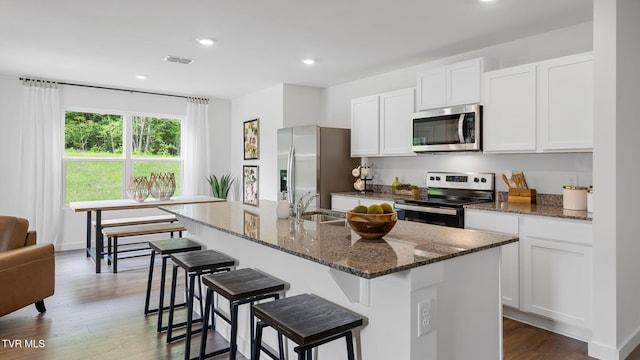 kitchen with appliances with stainless steel finishes, sink, a kitchen island with sink, and white cabinets