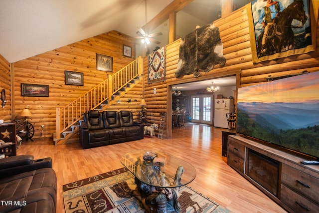 living room featuring rustic walls, ceiling fan, hardwood / wood-style floors, high vaulted ceiling, and french doors